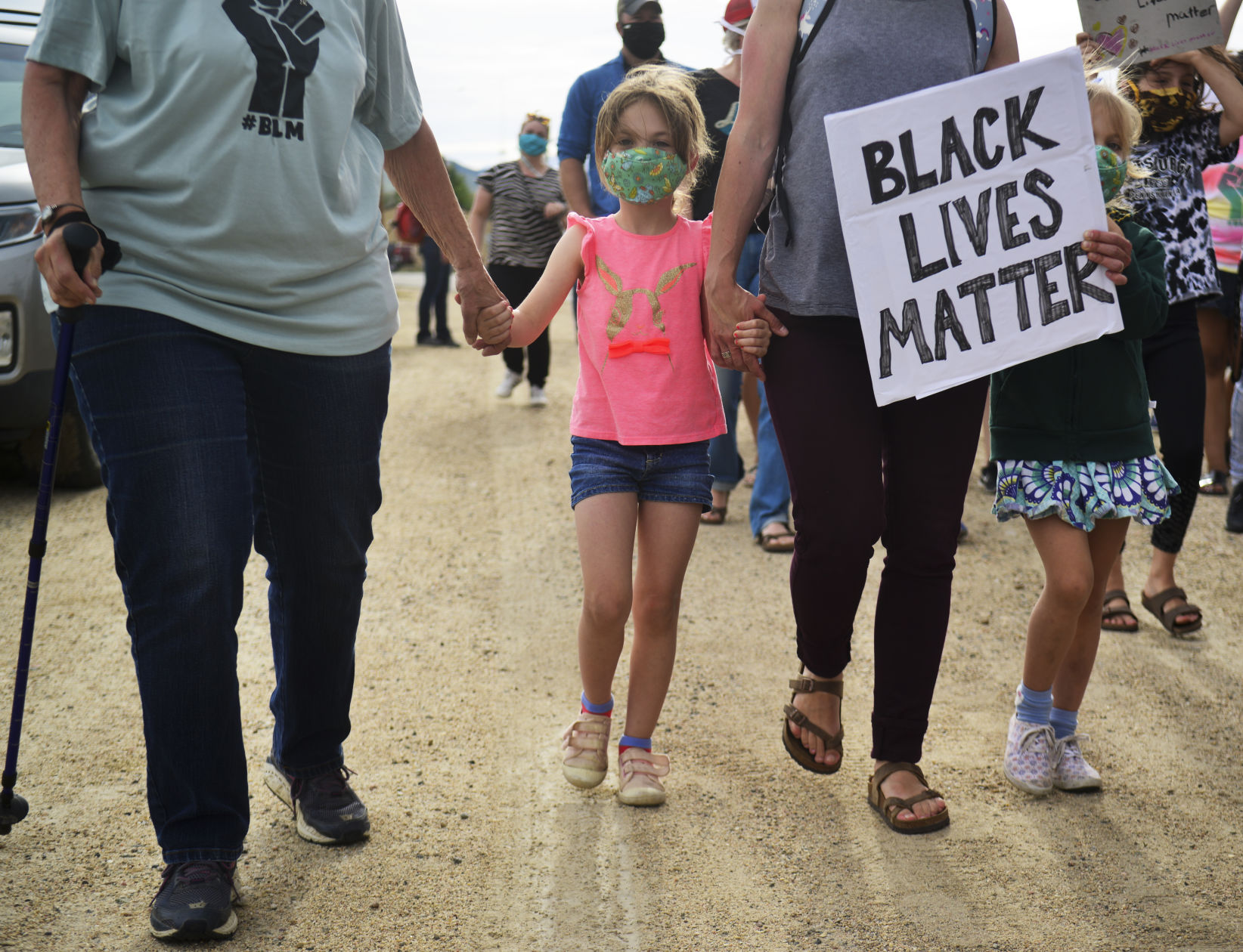 Joey Stadler, 6, center, holds hands with her grandma and mom while marching
